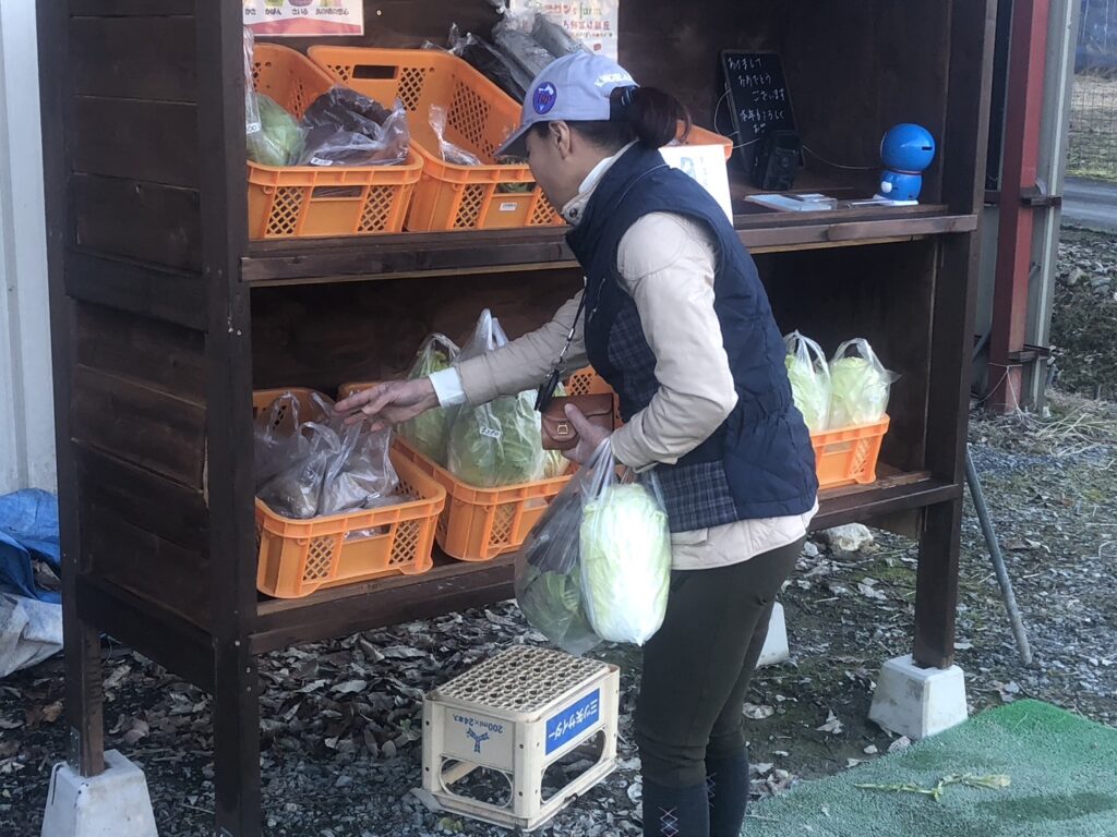 南丹市日吉町のコロン’sファーム無人販売所で野菜を手に取るお客様