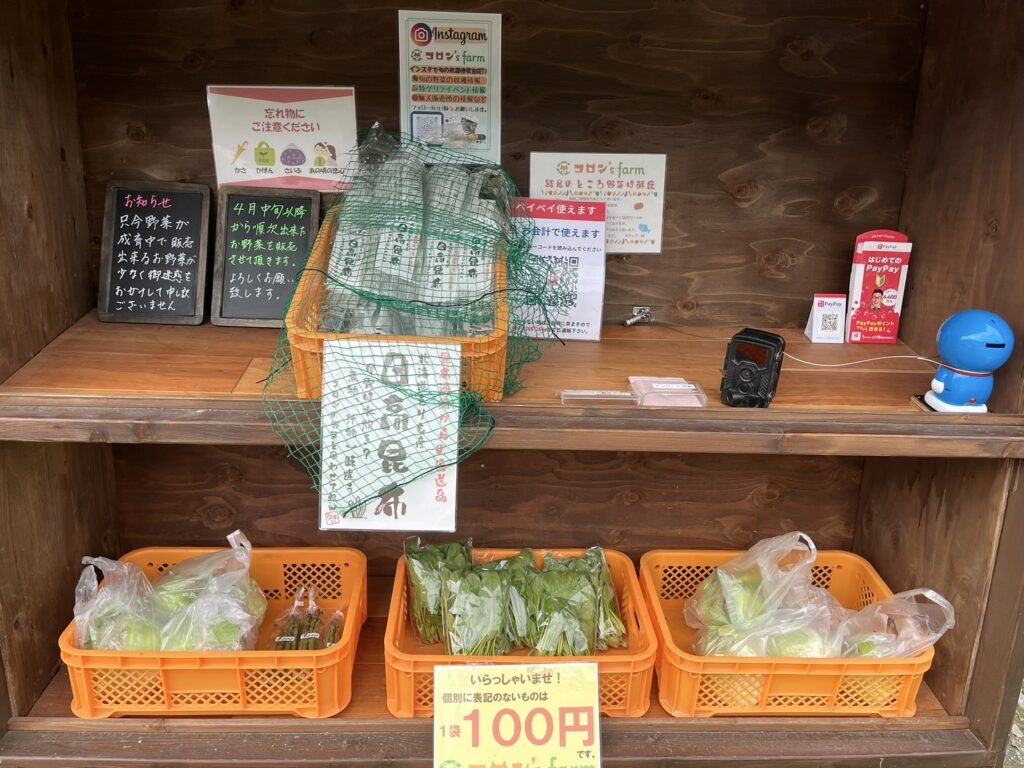南丹市日吉町のコロン’sファーム無人販売所に並ぶ旬野菜と案内板